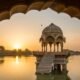 Scenic view of Gadisar Lake in Jaisalmer during sunset, showcasing temples and reflections.
